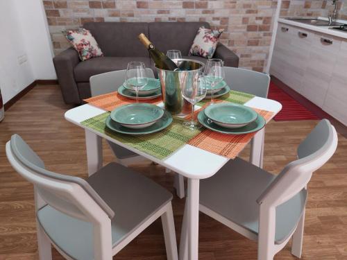 uma mesa de jantar branca com cadeiras e uma garrafa de vinho em Kalisa Home, B&B e Casa Vacanza Palermo em Capaci