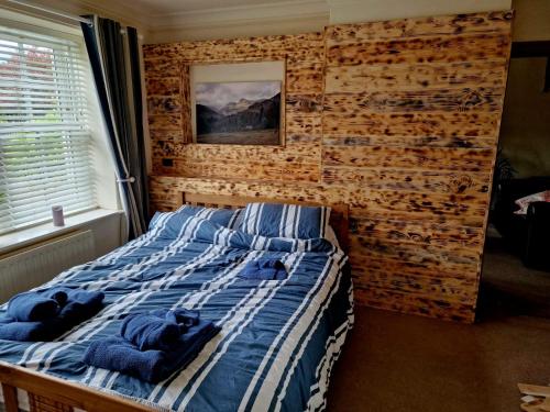 a bed in a bedroom with a wooden wall at Little half point in Welton