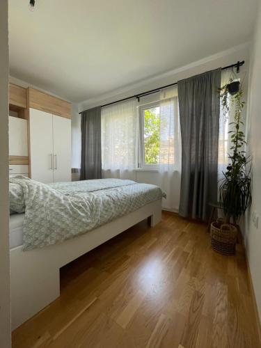 een slaapkamer met een bed en een groot raam bij Wild Green in Sarajevo