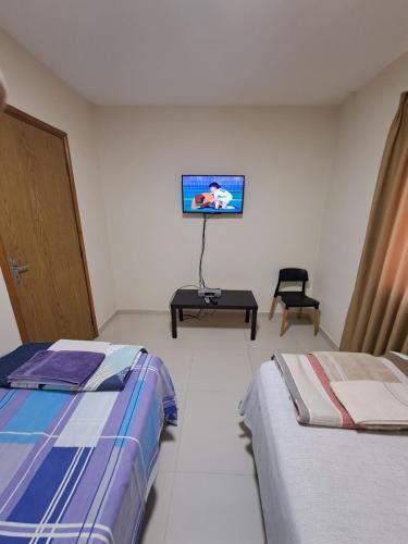 a room with two beds and a tv on the wall at Sur Backpackers in Santa Cruz de la Sierra