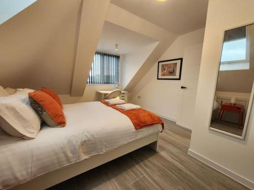 ein Schlafzimmer mit einem Bett mit orangefarbenen und weißen Kissen in der Unterkunft Paradigm Court, Modern 1-Bedroom Apartment, Oxford in Oxford