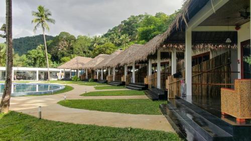 a row of resort buildings with a pool and trees at Bebeladan Beach Resort, In The Last Indigenous Corner in El Nido