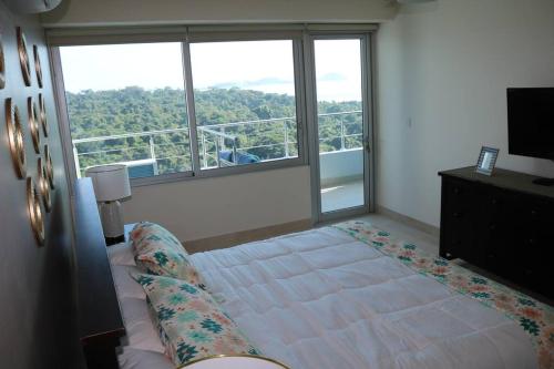 a bedroom with a bed and a large window at 16H Luxury Oceanview Playa Bonita Resort Panama in ArraijÃ¡n