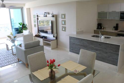a kitchen and living room with a table and chairs at 16H Luxury Oceanview Playa Bonita Resort Panama in ArraijÃ¡n