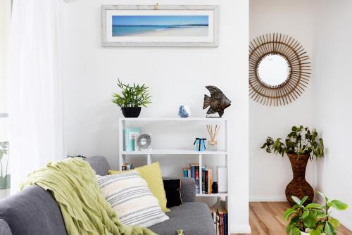 a living room with a gray couch and a mirror at Break Away in Burrill Lake