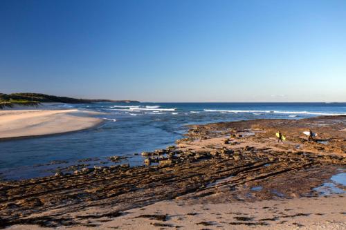 a group of people walking on a beach near the ocean at Break Away in Burrill Lake