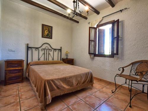 a bedroom with a bed and a window and a chair at Mountain Hideaway w Pool in Alfarnatejo