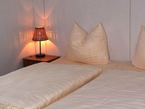 1 dormitorio con 2 camas, almohadas blancas y lámpara en Chalet in Gerolstein near Forest Trails, en Hinterhausen