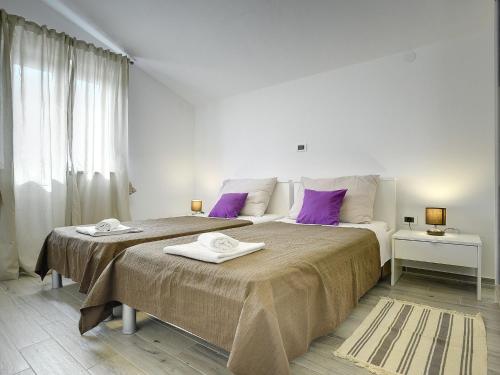 um quarto branco com uma cama grande e almofadas roxas em Detached, modern villa with private pool between Fazana and Pula, near beach em Valbandon