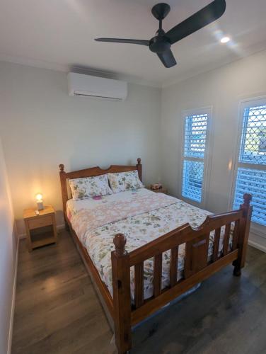 sypialnia z drewnianym łóżkiem i wentylatorem sufitowym w obiekcie Immaculate 2-Beds Entire House Chermside Brisbane w mieście Brisbane