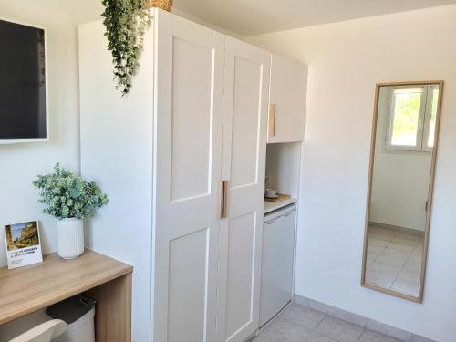 a kitchen with white cabinets and a mirror at Appartement double climatisé - Proche Tram & Centre in Montpellier
