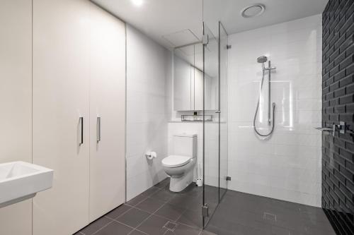 a white bathroom with a toilet and a shower at Orange Stay Apartments Potts Point in Sydney