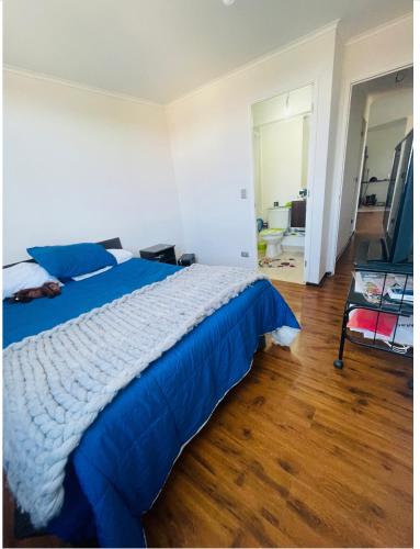 um quarto com uma cama azul e piso em madeira em A&L em Talcahuano