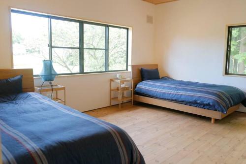 1 dormitorio con 2 camas y ventana grande en 1日1組様限定 黒姫山の絶景を楽しむ貸切サウナ付き一軒家 en Shinano