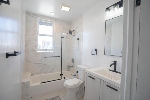 a white bathroom with a tub and a toilet and a sink at Burlington Hostel in Los Angeles