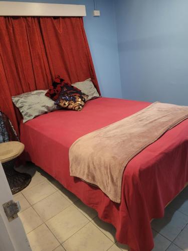 1 cama con manta roja y cortina roja en K&S Apartment en Singatoka