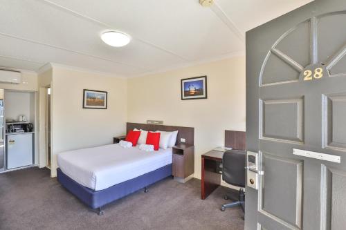 a bedroom with a bed and a desk and a door at Boulevard Motor Inn in Mildura