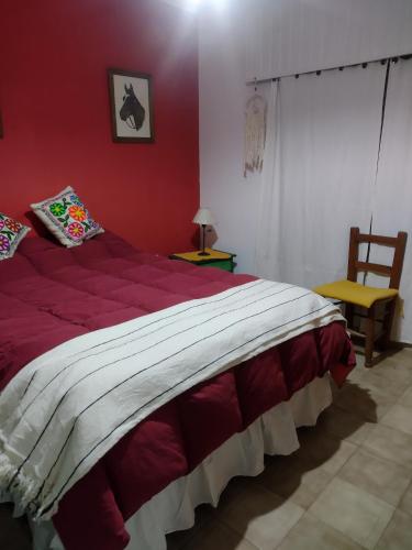 een rode slaapkamer met een bed en een stoel bij La Casa de Ana in San Antonio de Areco
