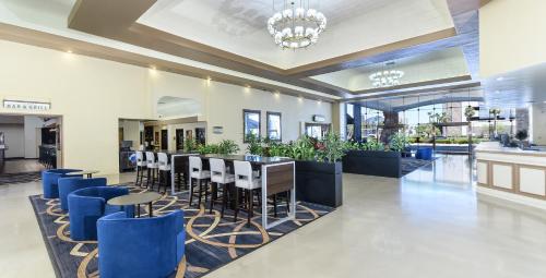 a lobby with a bar with blue stools at Alexis Park All Suite Resort in Las Vegas