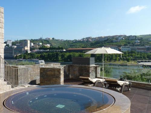 a swimming pool with an umbrella and chairs and a table at Vila Gale Collection Douro in Lamego