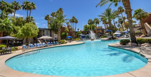 a swimming pool at a resort with palm trees at Alexis Park All Suite Resort in Las Vegas