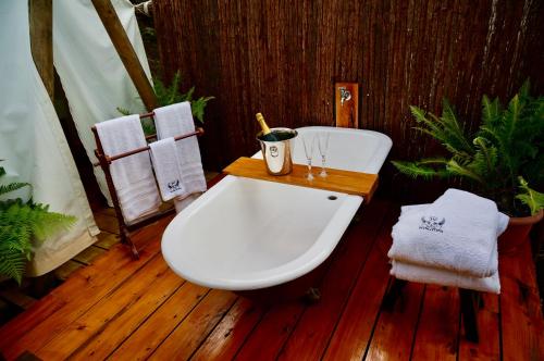 a bathroom with a white tub and a wooden floor at Wingtons Glamping in Clarence Point