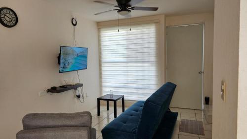 a living room with a blue couch and a ceiling fan at Allisson's House in Emiliano Zapata