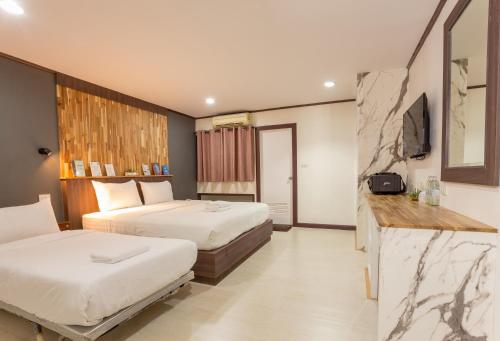 a hotel room with two beds and a television at Phimai Paradise Boutique Hotel in Nakhon Ratchasima