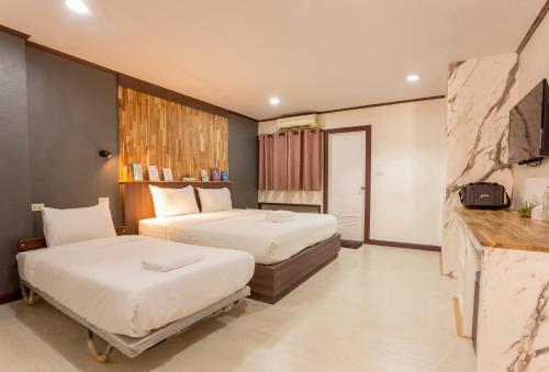 a hotel room with two beds and a television at Phimai Paradise Boutique Hotel in Nakhon Ratchasima