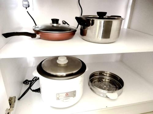 two pots and a slow cooker on a shelf at Kulai d putra suites beside ioiMall near JPO and Airport in Kulai