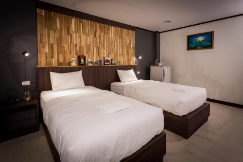 two beds in a hotel room with white sheets at Phimai Paradise Boutique Hotel in Nakhon Ratchasima