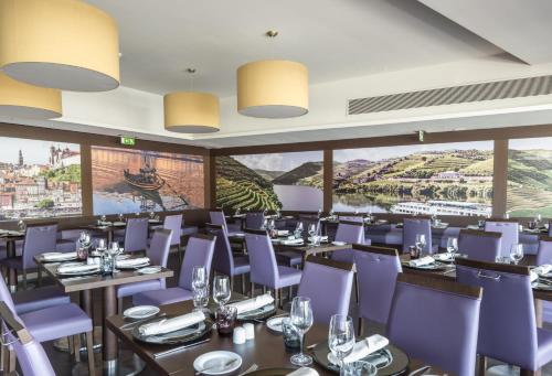 a restaurant with purple chairs and tables and windows at Vila Gale Collection Douro in Lamego