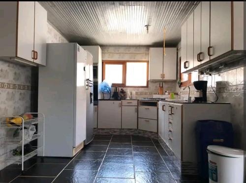 uma cozinha com armários brancos e piso em azulejo preto em Casa Nórdica em Taganga