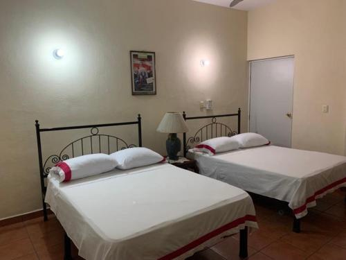 two beds sitting in a room with at Hotel Jacaranda in Tuxtla Gutiérrez
