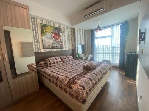 een slaapkamer met een bed in een kamer met een raam bij Comfy Apartment Grand Sungkon Lagoon in Dukuhpakis