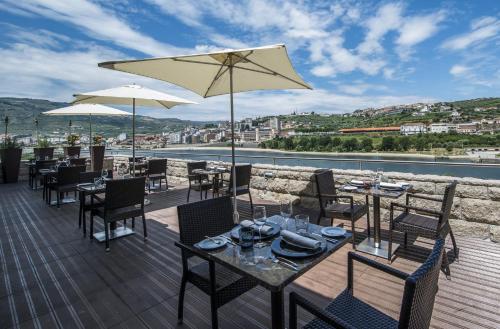a patio with tables and chairs and an umbrella at Vila Gale Collection Douro in Lamego