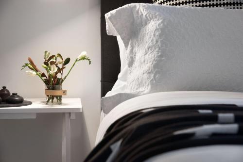 a bed with a pillow and a vase with flowers on a table at Campari in Daylesford
