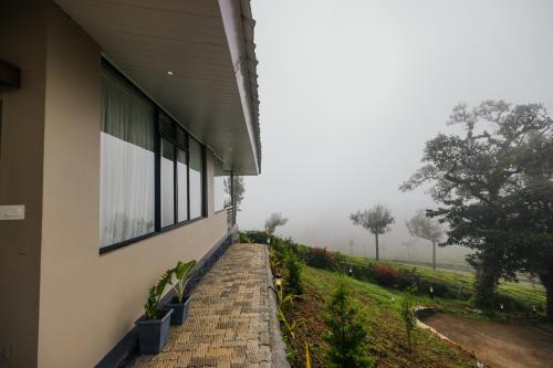 a building with windows and a view of a field at Misty Courtyard Resort in Chinnakanal