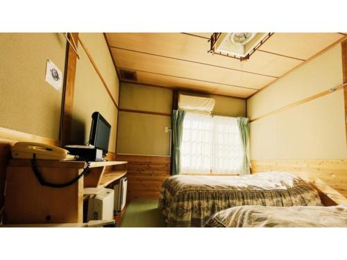 a hotel room with two beds and a television at Hakuba Pension Meteor - Vacation STAY 63342v in Hakuba