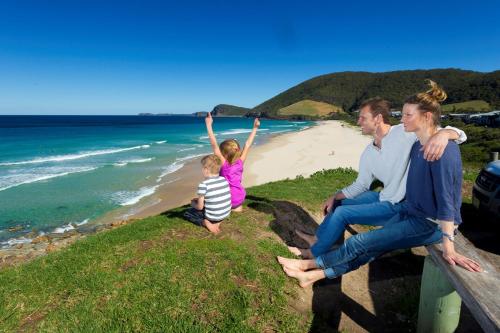 a family sitting on a bench at the beach at Blueys Retreat in Blueys Beach