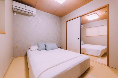 um quarto com uma grande cama branca e um espelho em mist - Japanese House with Private Outdoor Sauna em Osaka