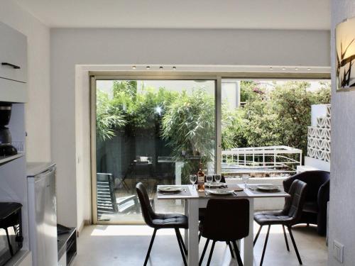 une cuisine avec une table et des chaises ainsi qu'une grande fenêtre dans l'établissement Appartement RDC à Villeneuve-Loubet - 2 Pièces, 45m², 4 Couchages, Plage à 100m - FR-1-252A-113, à Villeneuve-Loubet