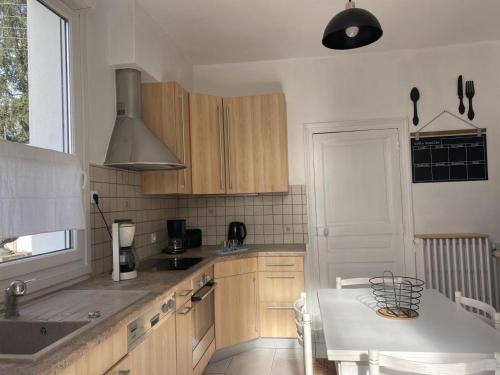 une cuisine avec des armoires en bois et un évier dans l'établissement Maison rénovée avec jardin à 20 min du centre historique de Moulins, proche LE PAL et Vichy - FR-1-489-469, à Moulins