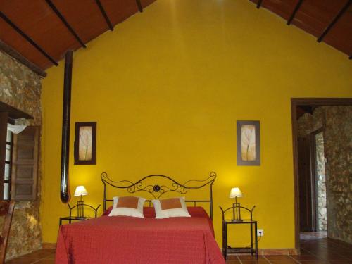 Dormitorio amarillo con cama y pared amarilla en Set of rural houses in the center of Andalucia, en Humilladero