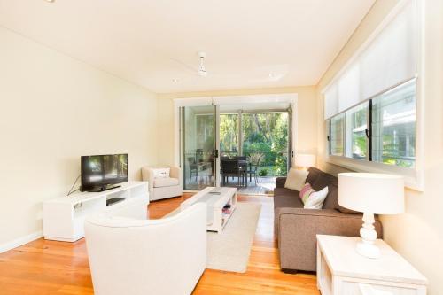 a living room with a couch and a tv at Blueys Retreat in Blueys Beach