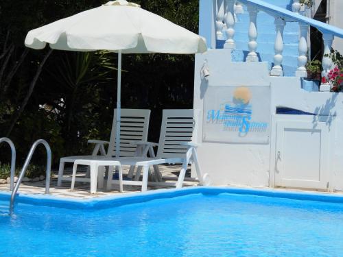 a pool with a table and an umbrella and chairs at Holiday apartment with sea view and mountains view in Marathokampos