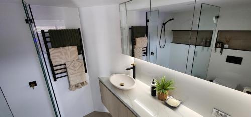 a white bathroom with a sink and a shower at Casa del Sol Caloundra in Caloundra
