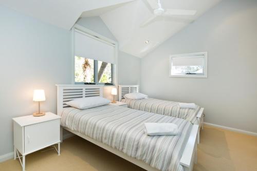 two beds in a white room with two windows at Blueys Retreat in Blueys Beach