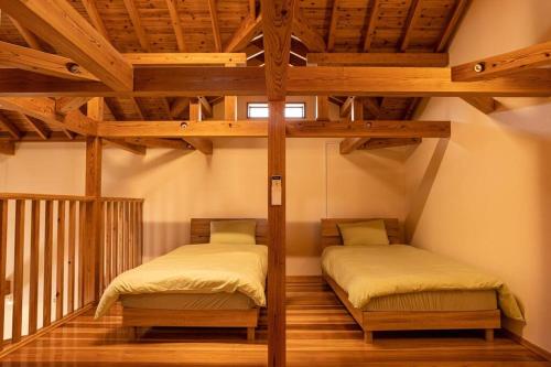 two twin beds in a room with wooden ceilings at Nakijin Lodge ぺんさじょうやー in Nakijin