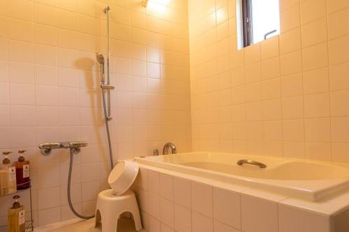 łazienka z wanną, toaletą i prysznicem w obiekcie Nakijin Lodge ぺんさじょうやー w mieście Nakijin